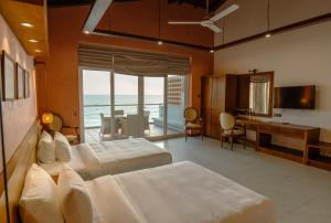 a bedroom with two beds and a desk and a dining room at At Kelly's Ambalangoda in Ambalangoda +47 photos