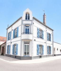 a white building with blue shutters on a street at Cap Canche in Étaples