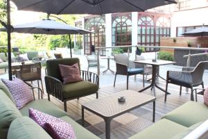 eine Terrasse mit Stühlen, Tischen und Sonnenschirmen in der Unterkunft arte Hotel Linz in Linz