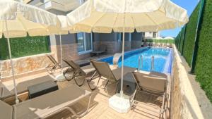 a pool with chairs and umbrellas next to a house at Hillfort Suites Apart Otel in Demre