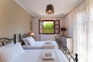 a bedroom with two beds and a window at Lindos Aeonian Villas in Lindos +15 photos
