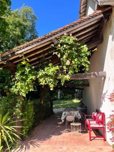 a pergola with a red bench and flowers at Le Clos du Cerf in Cellettes