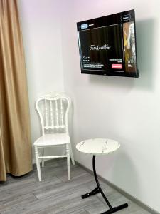 a white chair and a tv on a wall at Le Charme Boutique in Bucharest