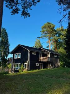 a black house sitting on top of a lush green field at Norppa Lake Resort in Savonlinna