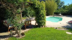 a pool with a table and a chair in a yard at La Belgastide chambre d'hôte in Quins