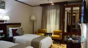 una habitación de hotel con dos camas, una mesa y sillas en Macau Masters Hotel, en Macau