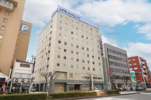 a tall white building on a city street at Dormy Inn Tsu in Tsu