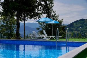 two chairs and an umbrella next to a swimming pool at Shavsheti view Cottage in Didachara