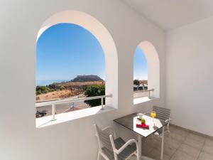 una sala da pranzo con un tavolo e due finestre di Lindos Portes Suites - Adults Only a Líndos