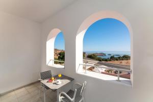 una sala da pranzo con un tavolo e due finestre con vista di Lindos Portes Suites - Adults Only a Líndos