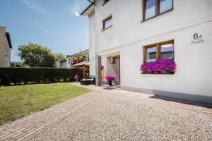 a white house with purple flowers in a window at BOSMAN Karwia - Pokoje 100m od Plaży in Karwia