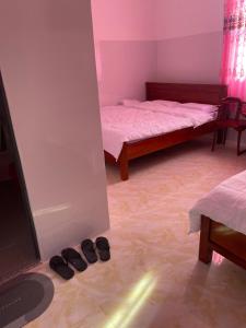 a bedroom with two beds and shoes on the floor at Khách Sạn Thành Châu 2 