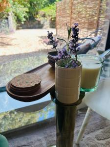 a table with a vase with purple flowers on it at Between hills and home in Trooz