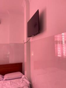 a bedroom with a pink wall with a tv on the wall at Khách Sạn Thành Châu 2 