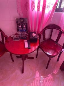 a red table with two chairs and a room with pink curtains at Khách Sạn Thành Châu 2 