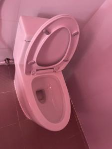 a pink toilet with the seat up in a bathroom at Khách Sạn Thành Châu 2 