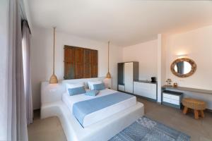 una camera da letto bianca con un grande letto e uno specchio di Lindos Portes Suites - Adults Only a Líndos