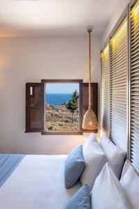 a bedroom with a large bed and a window at Lindos Del Mar Suites - Adults Only in Lindos