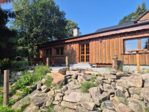 a log cabin with a rock wall in front of it at Zátiší na pomezí in Bukovec