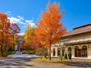 a tree with orange leaves in front of a building at Hotel Floracion Nasu in Nasu