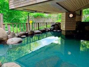 a pool of water with rocks and a bridge at Hotel Floracion Nasu in Nasu +61 photos