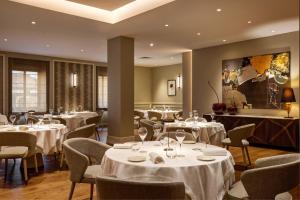 a restaurant with white tables and chairs and a painting at Antum Hotel in Benevento