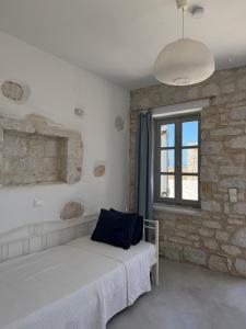 a bedroom with a bed and a stone wall at LA MAISON D'HELENE in Naousa