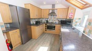 a kitchen with wooden cabinets and a stainless steel refrigerator at Cloudbreak Hot Tub Log Burner Dogs Welcome in Braunton
