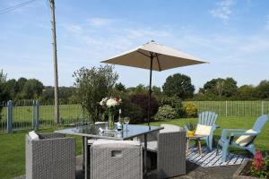 a patio table with an umbrella and chairs at Blackberry Barn in Wotton-under-Edge