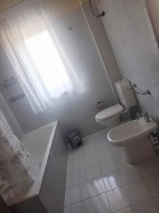 a white bathroom with a toilet and a window at The Citrus Balcony in Trappitello