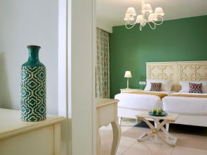 - une chambre avec un lit blanc et un mur vert dans l'établissement Anemos Luxury Grand Resort, à Georgioúpoli
