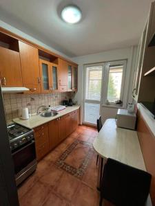 a kitchen with wooden cabinets and a table and a sink at BardiHome in Bardejov