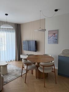 a living room with a table and chairs and a television at Apartament Lake Mood Iława in Iława