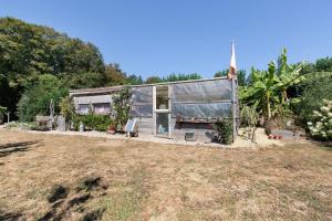 a small house with a greenhouse in a yard at Caravane au jardin in Brix