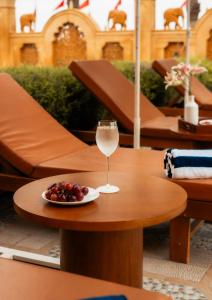 a glass of wine and a plate of fruit on a table at Chokhi Dhani The Palace Hotel in Jaisalmer