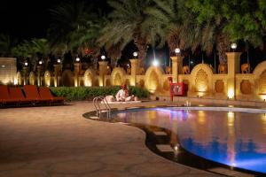 a man sitting next to a swimming pool at night at Chokhi Dhani The Palace Hotel in Jaisalmer