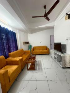 a living room with two couches and a tv at Aura Suites Chernallur in Ernakulam