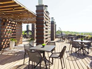 eine Terrasse mit Tischen und Stühlen auf einem Deck in der Unterkunft IBIS Styles Kaunas Centre in Kaunas