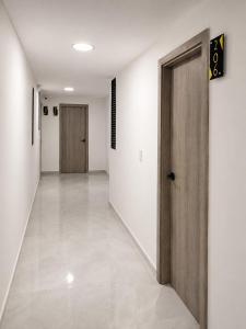 a hallway with white walls and a wooden door at Qantic Lodging & Rooftop in Medellín
