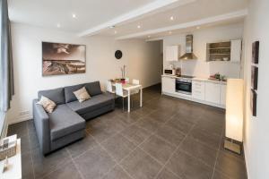 a living room with a gray couch and a kitchen at Apart'Hotel Liège City Centre in Liège