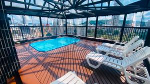 a deck with two chairs and a swimming pool at Cobertura Duplex Vista Cidade Centro TV4061 in Blumenau