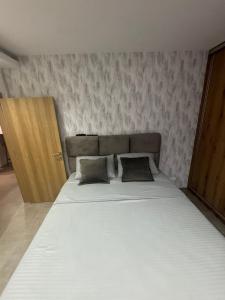 a bedroom with a large bed and a wooden door at Omnia Lux Apartman 4C in Šabac