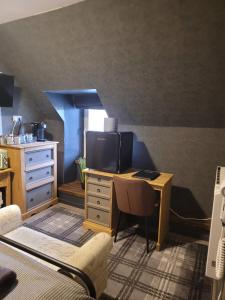 a bedroom with a desk with a tv and a bed at BELLFIELD HOUSE in Broadford