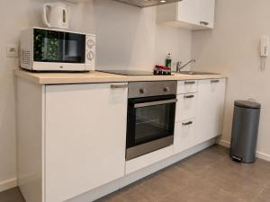 a white kitchen with a microwave and a stove at Apart'Hotel Liège City Centre in Liège