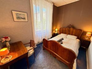 a bedroom with a wooden bed and a table at L'intemporel Chez Mémé - Centre - Saint Etienne in Saint-Étienne
