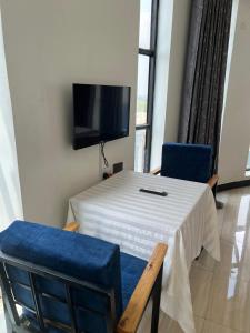 a room with a table and two chairs and a flat screen tv at KH KH Hotel in Kasese