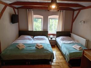 two beds in a room with two windows at Zacisze Trzech Gór- klimatyczne noclegi i restauracja in Jedlina-Zdrój