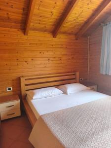 a bedroom with a bed in a wooden room at Guesthouse Vila Druri Dhermi in Dhërmi