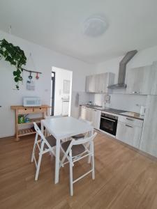 a kitchen with a white table and chairs in it at Casa Timavo in Ronchi dei Legionari