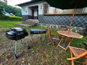 a grill and a picnic table with a table and chairs at Matsunokitei Chalet Irori in Otari